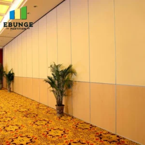 Long hallway with tall beige partition walls, patterned carpet, and potted plants; logo reading 'EBUNGE PARTITION' in the upper left corner.