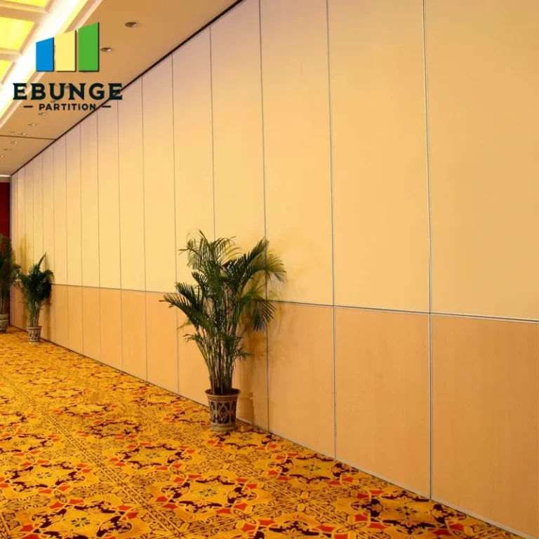 Long hallway with tall beige partition walls, patterned carpet, and potted plants; logo reading 'EBUNGE PARTITION' in the upper left corner.